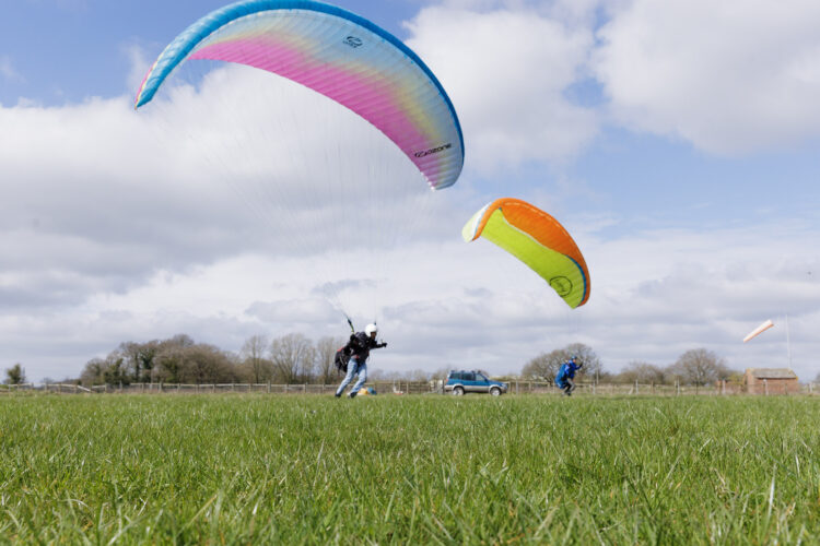 Paragliders flying above open ground